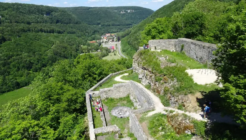 Ruinen der Burg Hohenwittlingen, umgeben von grünen Wäldern, mit einem Dorf im Tal.