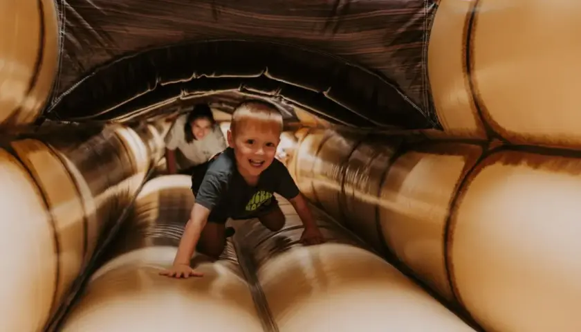Ein Junge krabbelt lachend durch einen aufblasbaren Tunnel. Ein toller Spaß für **Bayreuth mit Kindern**!