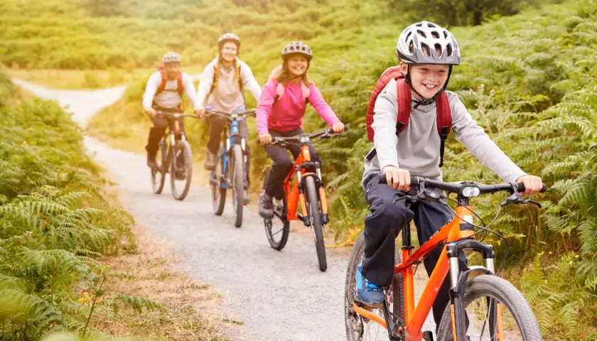 Fröhliche Familie auf einer Fahrradtour mit Kindern durch eine grüne Landschaft.
