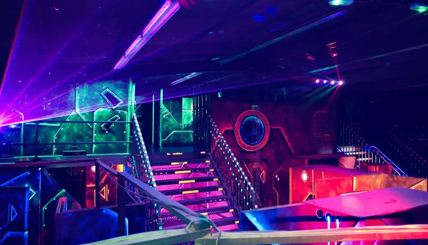 Futuristische Halle mit bunten Lichtern und Lasern. Ein aufregender Ort für Schwarzlicht Minigolf in Heidelberg.