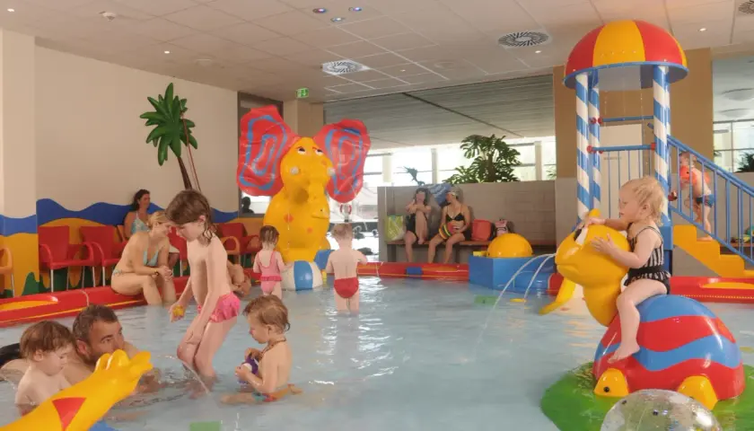Fröhliche schwimmbad kinder planschen im Wasser, spielen mit bunten Figuren und rutschen. Ein Elefant und eine Schildkröte sorgen für Spaß.