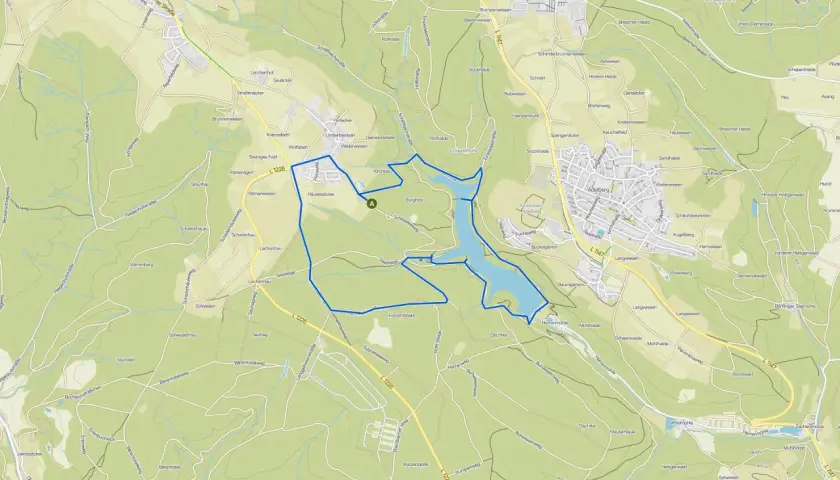 Der Herrenbachstausee mit seiner Kugelbahn-ähnlichen Uferlinie, eingebettet in grüne Hügel und Wälder.