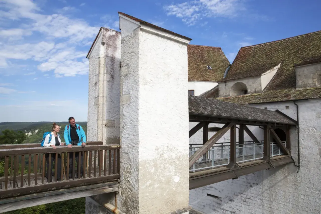 Ein Paar genießt den Ausblick von der Holzbrücke der Burg Wildenstein im Donautal.