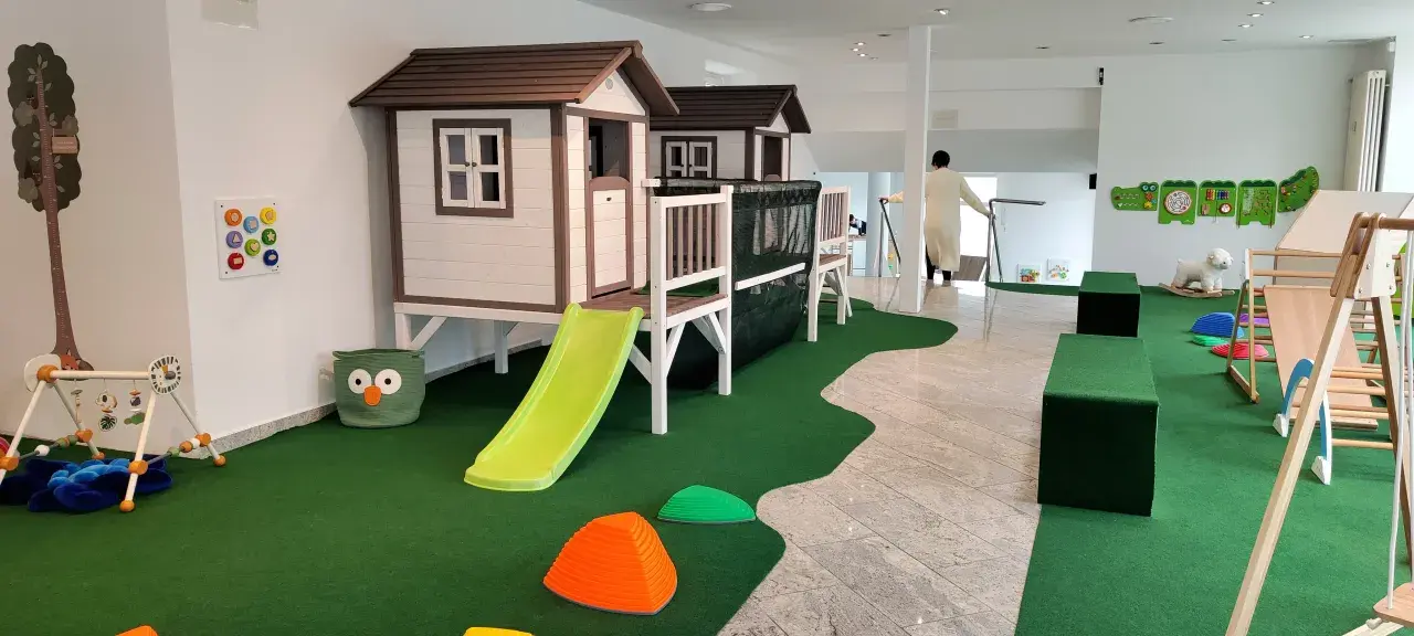 Einladendes **Cafe mit Spielplatz**: Zwei Spielhäuser mit Rutschen, Klettergerüst, Spielzeug und Sitzgelegenheiten für Kinder.