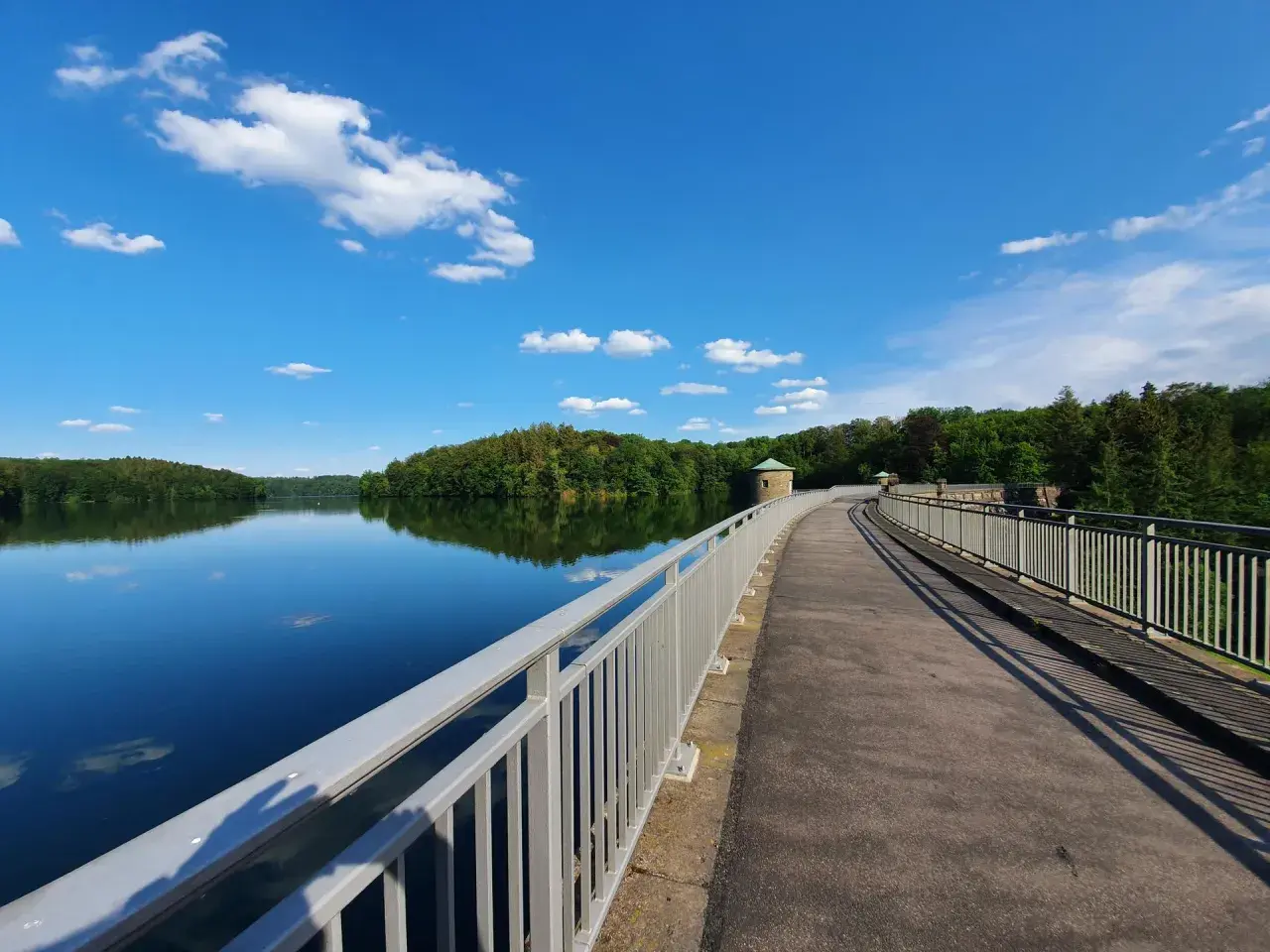 Ein idyllischer Weg führt über eine Staumauer am See. Perfekt für Ausflugsziele Oberbergischer Kreis mit Kindern, um die Natur zu genießen.
