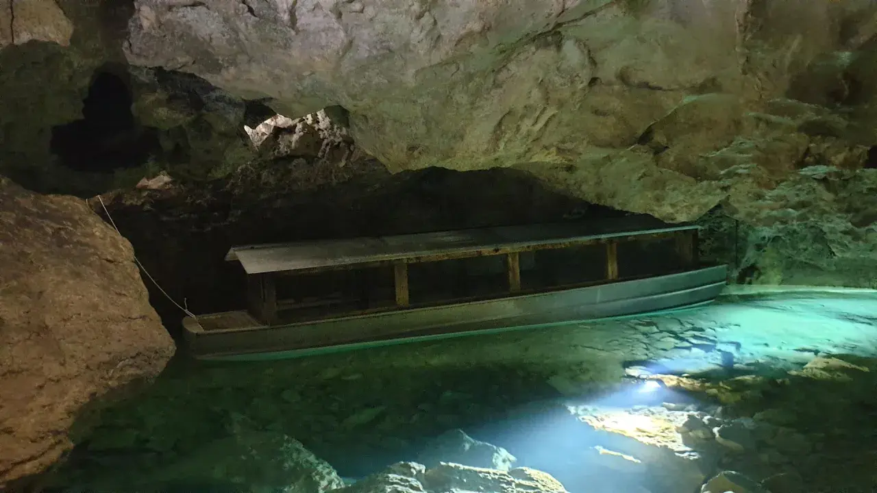Ein Boot wartet auf Besucher in der Höhle der Zwiefalter Aach. Das klare, grüne Wasser schimmert im Licht.