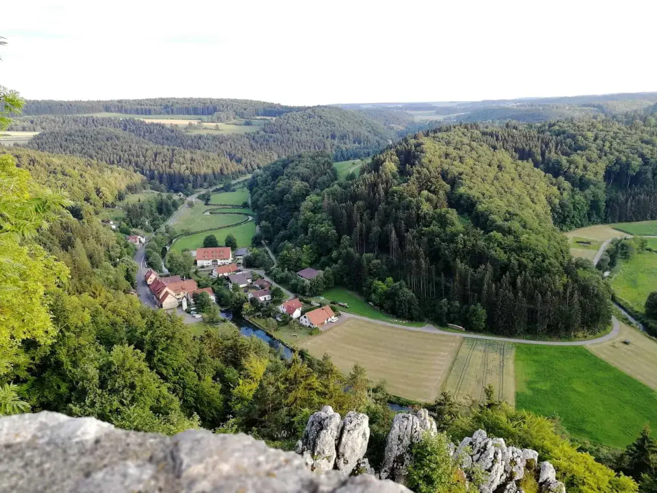 Idyllisches Lautertal Alb mit kleinen Dörfern, Flüssen und bewaldeten Hügeln, aufgenommen von einem Felsvorsprung.