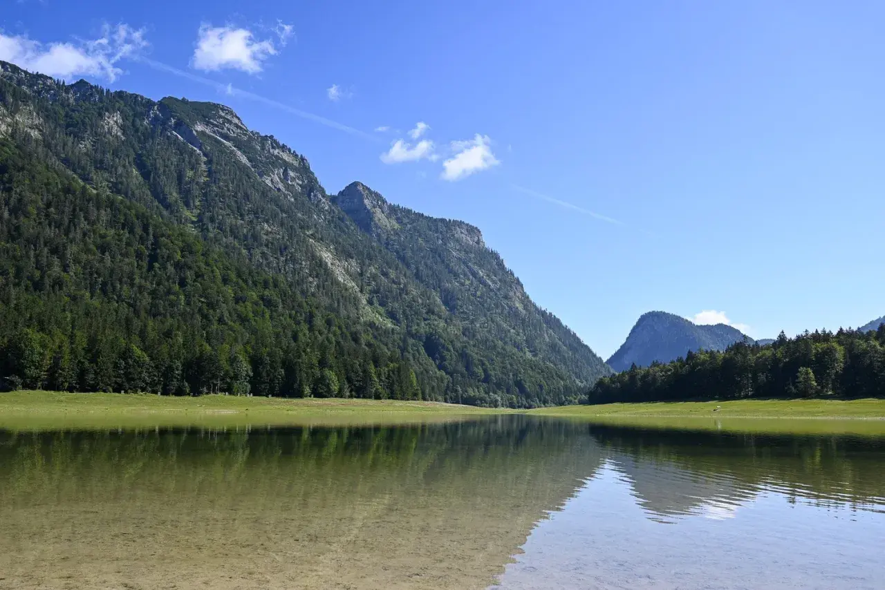 Spiegelglatte See mit Bergkulisse und Wald. Perfekt für eine Wanderung auf dem weitsee rundweg.