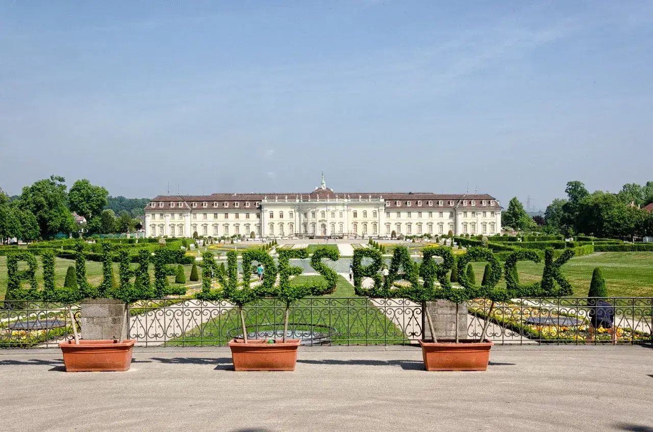 Blühendes Barock im Ludwigsburg Park: Ein prächtiges Schloss mit kunstvoll geschnittenen Hecken, die das Wort "Barock" formen.