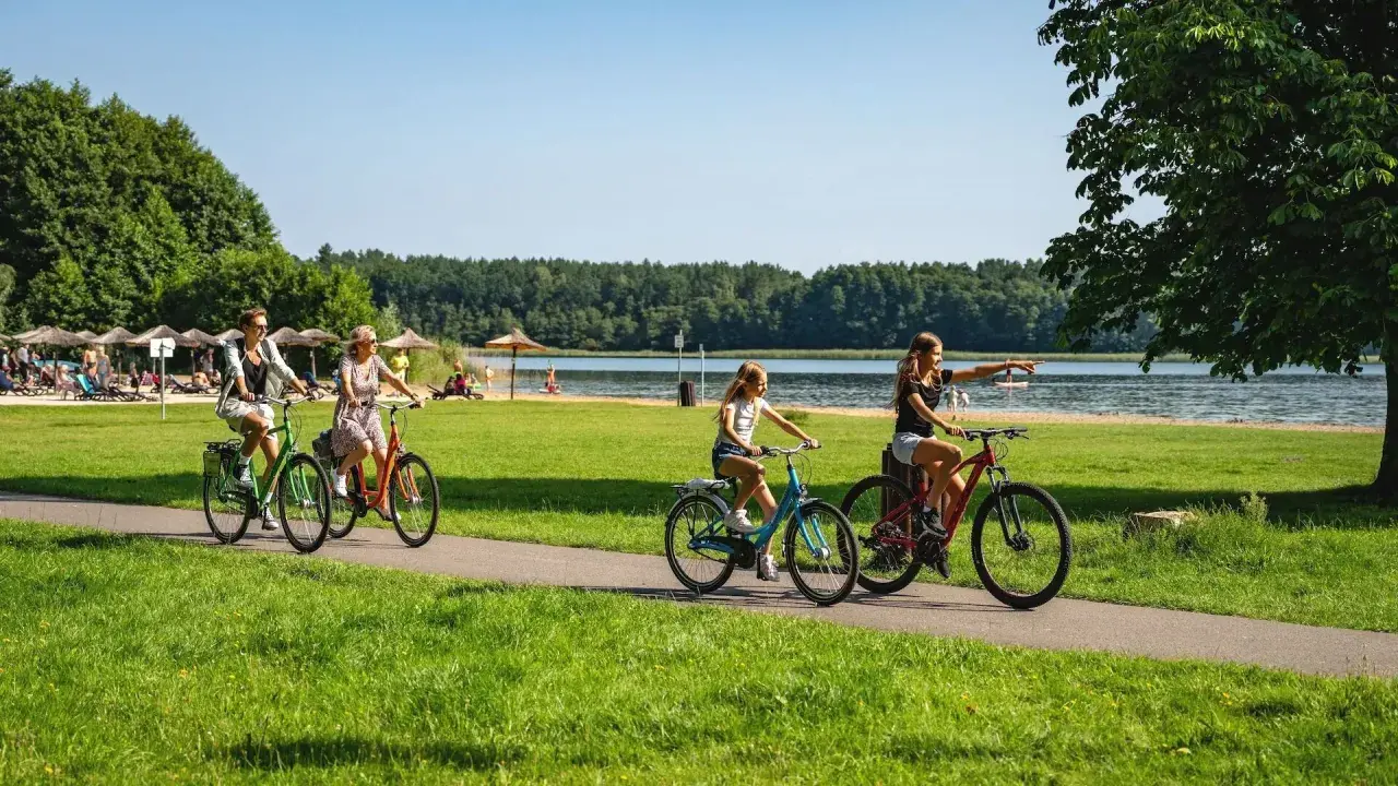 Familie genießt einen sonnigen Urlaub in Brandenburg mit Kindern, radelt am See entlang.