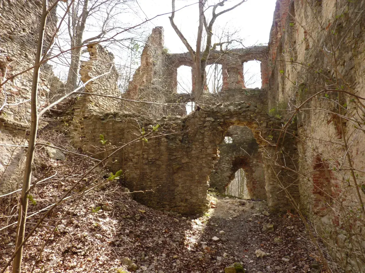 Verfallene Burgruine mit steinernen Mauern und Bögen, die wie ein hoher Turm in den Himmel ragt.