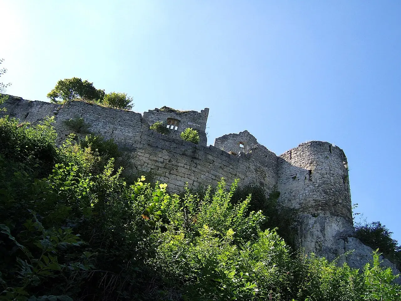 Ruinen der Burg Hohenurach ragen über üppiges Grün empor, ein steinerner Zeuge vergangener Zeiten unter blauem Himmel.