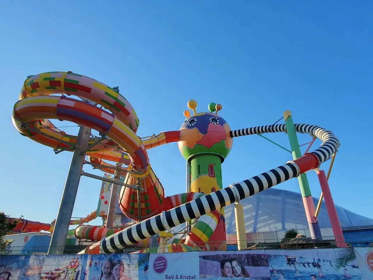 Bunte Miramar Rutschen schlängeln sich vor blauem Himmel. Ein fantasievolles Gebilde mit bunten Röhren und einem lustigen Kopf.