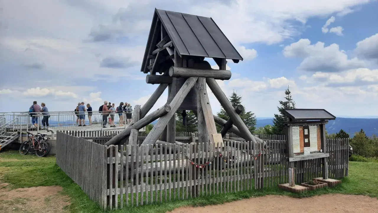 Besucher genießen Aussicht am Glockenturm, einem der vielen Ausflugsziele im Erzgebirge. Fahrräder stehen bereit für weitere Erkundungen.