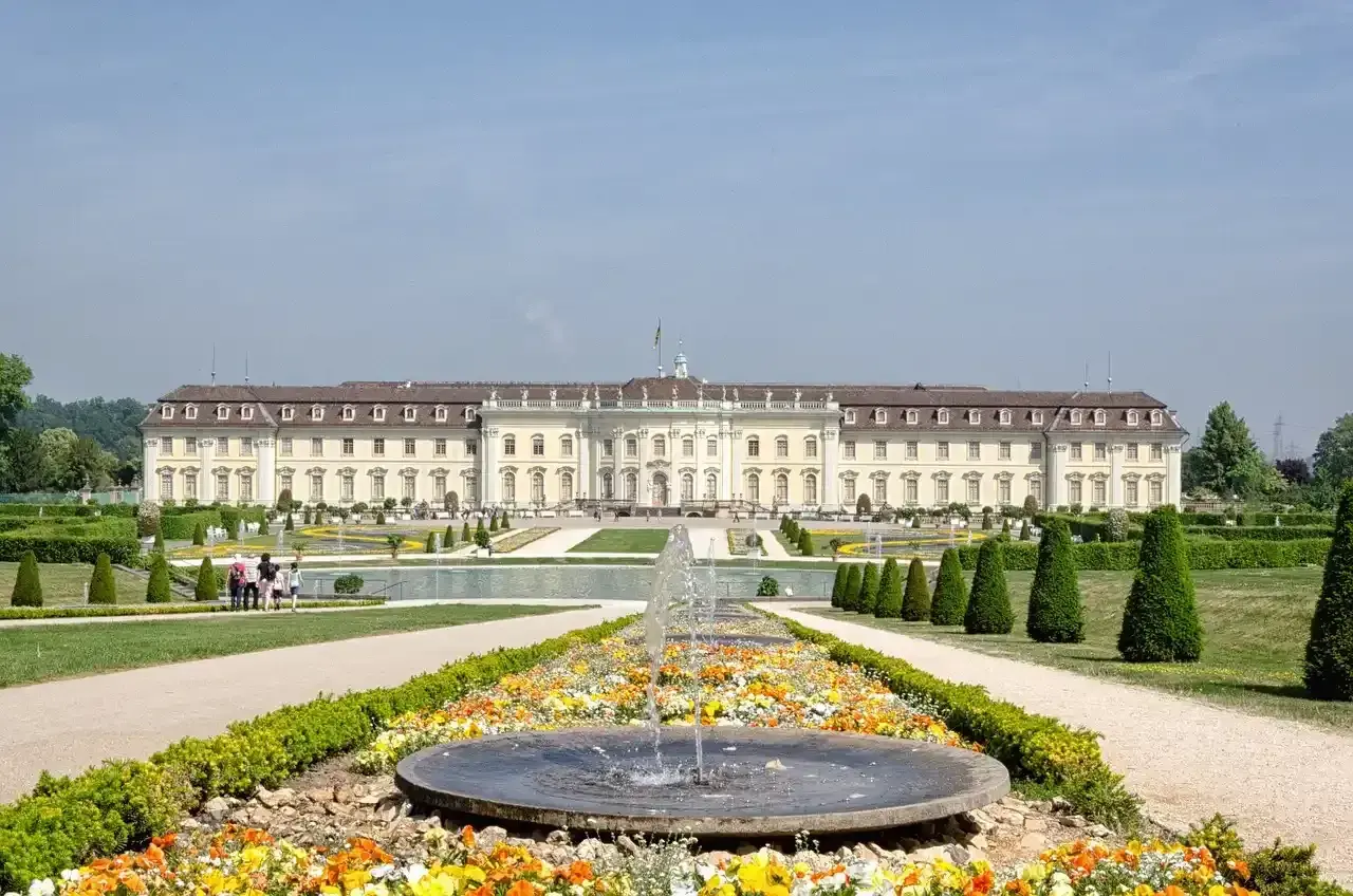 Prachtvolles Barockschloss Ludwigsburg mit symmetrischen Gärten und einem blühenden Blumenbeet vor einem Brunnen.