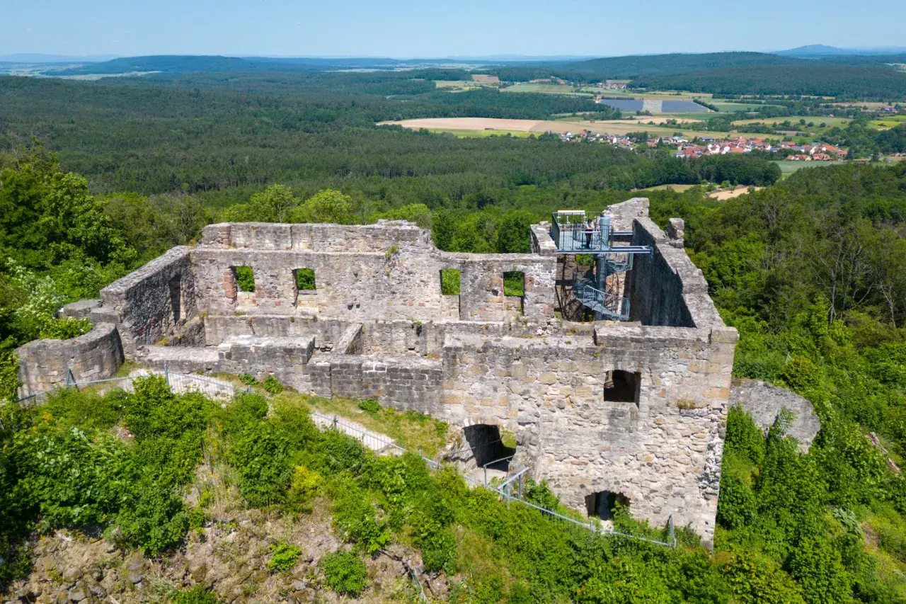 Die **Ruine Bramberg** thront auf einem bewaldeten Hügel. Steinmauern mit leeren Fensterhöhlen und eine Wendeltreppe zeugen von vergangener Pracht.