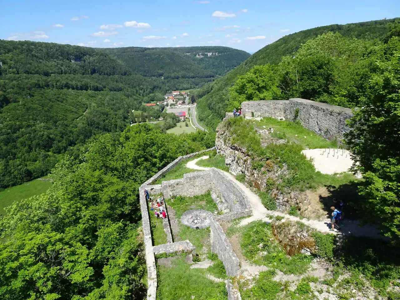 Ruinen der Burg Hohenwittlingen, umgeben von grünen Wäldern, mit einem Dorf im Tal.