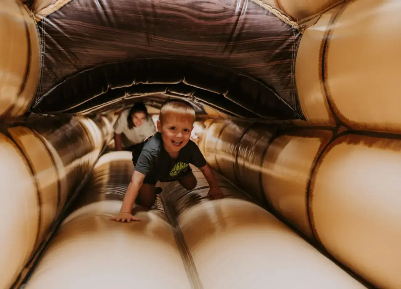 Ein Junge krabbelt lachend durch einen aufblasbaren Tunnel. Ein toller Spaß für **Bayreuth mit Kindern**!