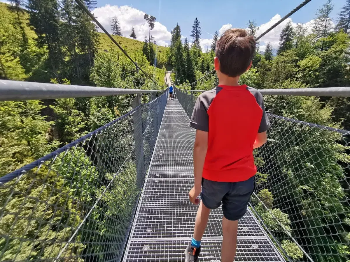 Junge auf Hängebrücke, ein Abenteuer bei einer leichten Wanderung mit Kindern in Bayern.
