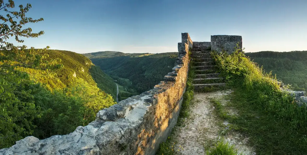 Sonnenbeschienene Ruinenmauer und Treppen mit Blick ins Grüne Tal der Wolfsschlucht bei Bad Urach.