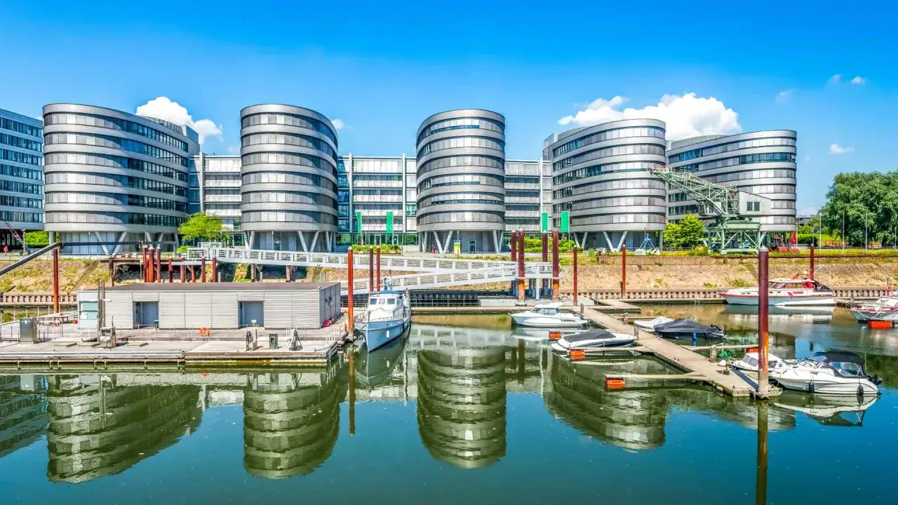 Moderne Gebäude am Wasser mit Booten im Hafen. Hier kann man in Duisburg eine Bootsfahrt machen und die Architektur genießen.