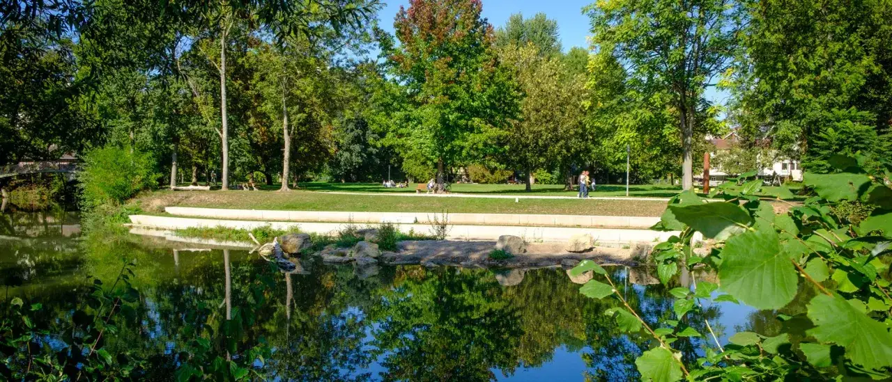 Idyllischer Park mit Teich und B&auml;umen, Menschen genie&szlig;en die Sonne im Talaue Waiblingen.