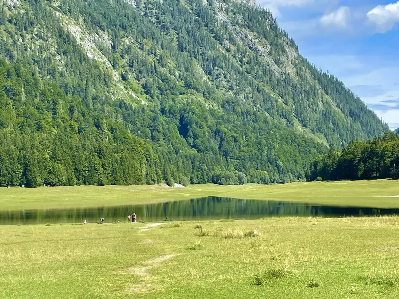 Idyllische Berglandschaft mit See und grünen Wiesen. Menschen genießen das Wandern Winklmoosalm.