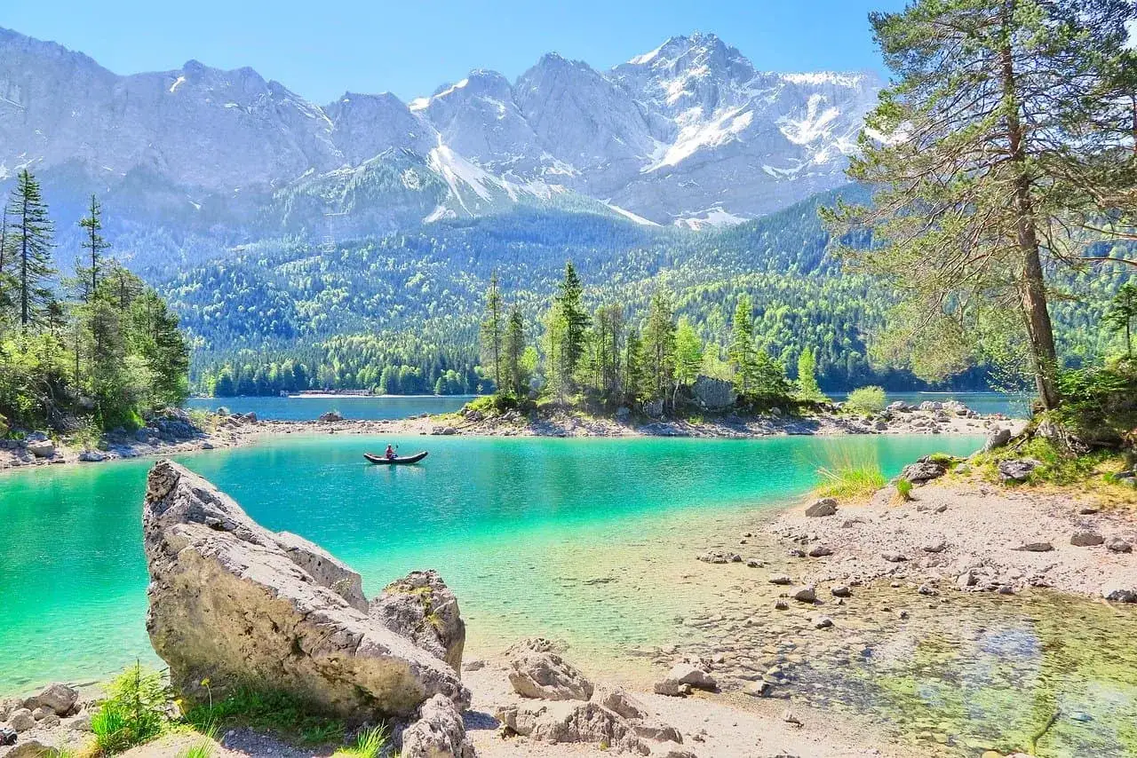 Ein Kanufahrer genießt die Ruhe auf einem türkisfarbenen See vor majestätischen Bergen. Perfekter Urlaub in Deutschland!