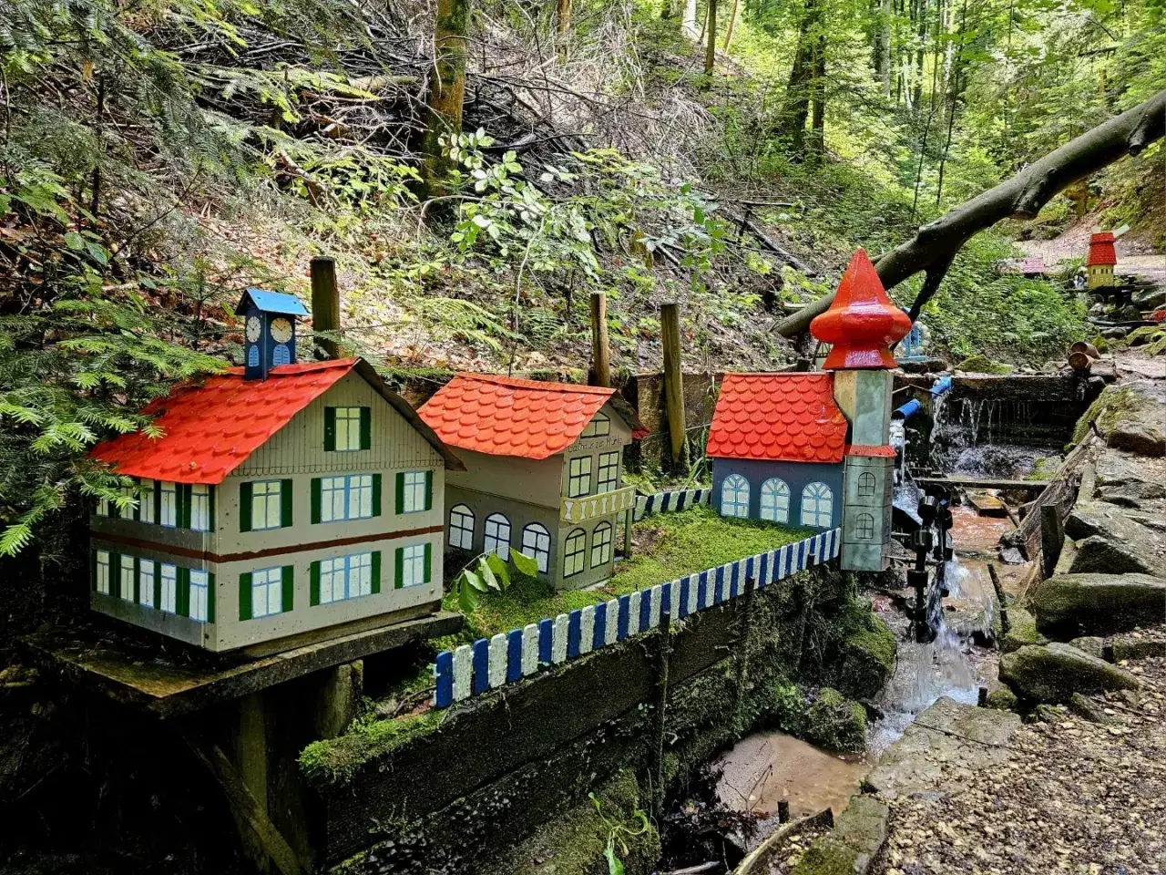 Miniaturhäuser mit roten Dächern am Bachlauf der Schelmenklinge Lorch, ein märchenhafter Anblick im Wald.