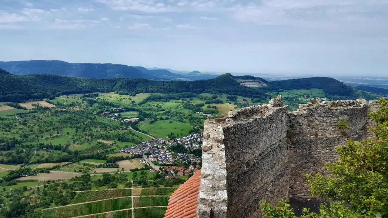 Blick von Burgruine Hohenneuffen auf ein gr&uuml;nes Tal mit Weinbergen und Dorf. Eine tolle Hohenneuffen Wanderung!