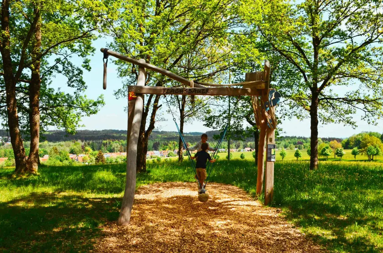 Kinder schaukeln auf einem Spielplatz in Leutkirch. Ein sch&ouml;ner Ort zum Wandern und Spielen.