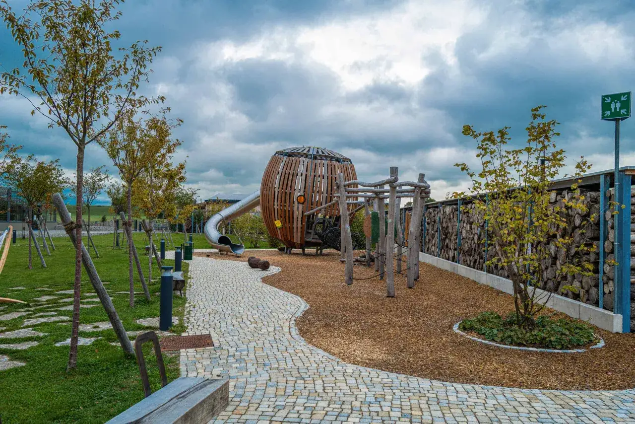 Ein Spielplatz, der an die Rapunzel Welt erinnert, mit einer Rutsche, einem Klettergerüst und einem großen Holzkugel-Turm.