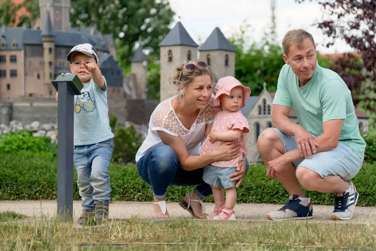 Familie erkundet Wernigerode mit Kindern. Ein kleiner Junge zeigt begeistert auf die Miniatur-Burgen, während seine Eltern und die kleine Schwester fasziniert zuschauen.
