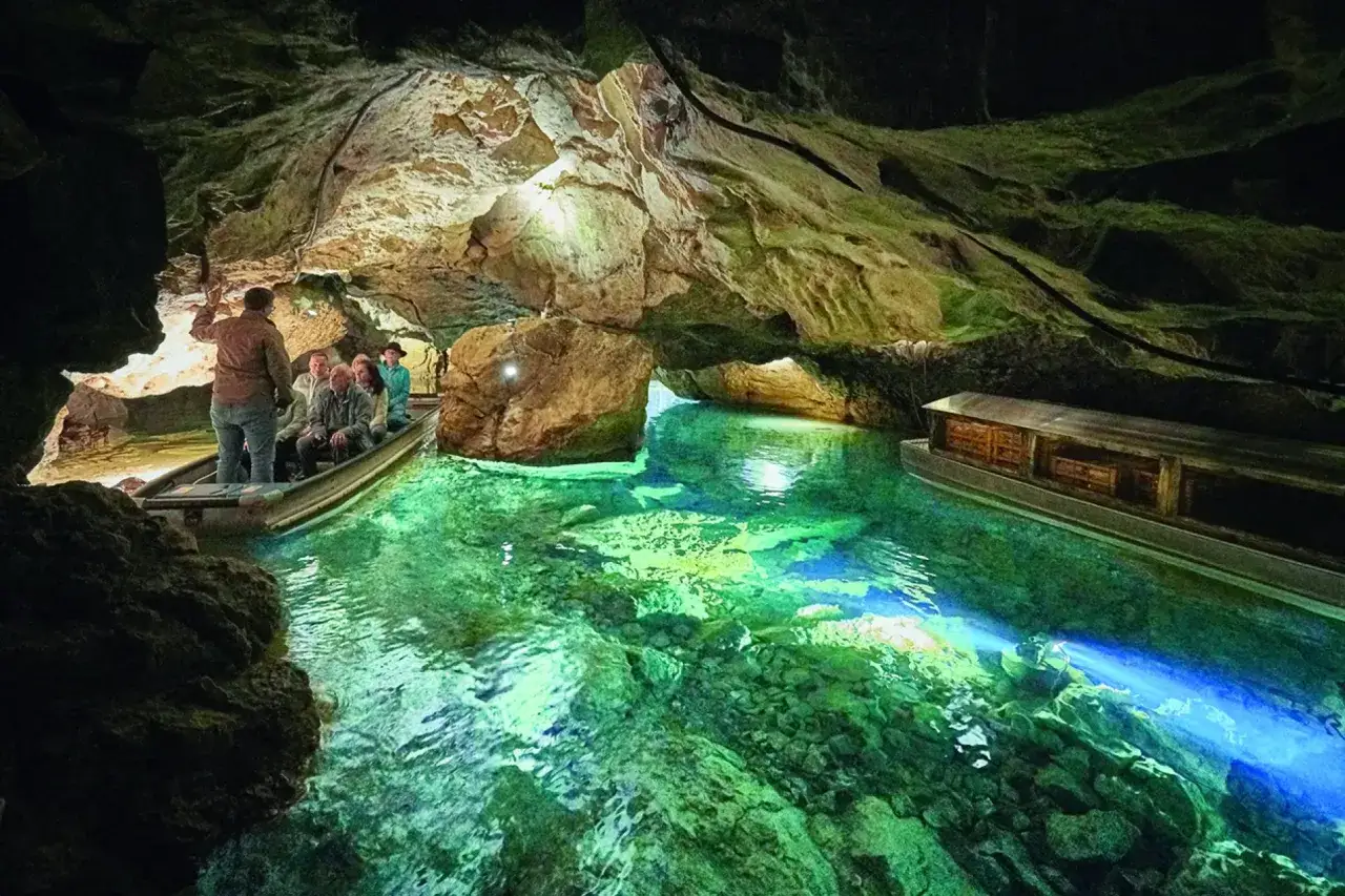 Bootsfahrt durch die H&ouml;hle der Zwiefalter Aach. Besucher bestaunen das smaragdgr&uuml;ne Wasser und die Felsformationen.