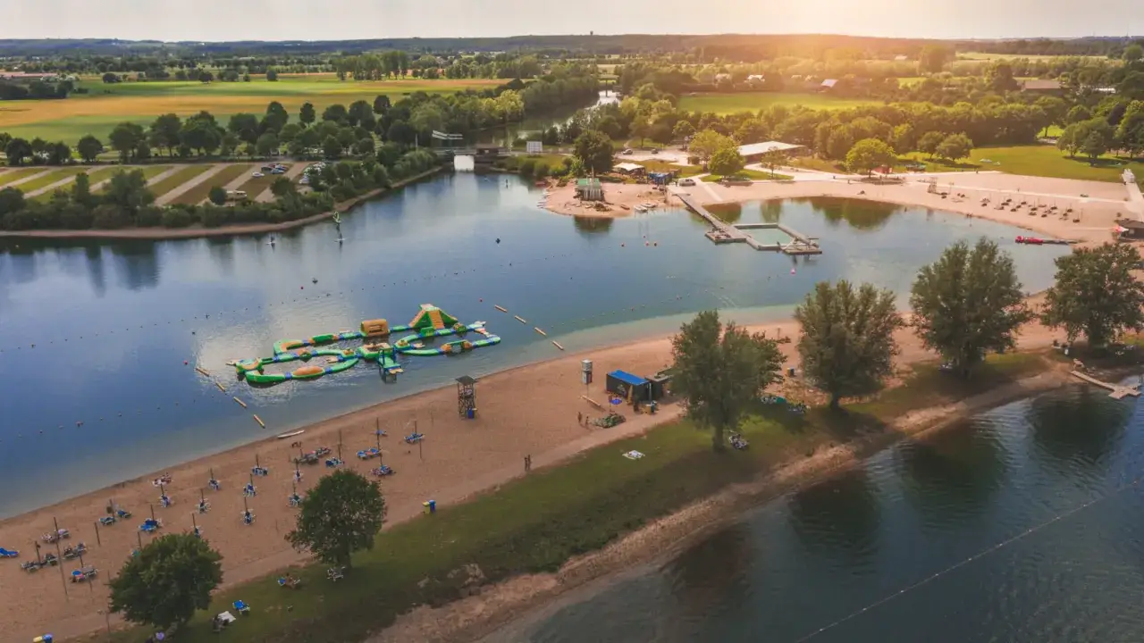 Sommerliche Ausflugsziele Niederrhein: Badesee mit Wasserrutsche, Strand und Liegestühlen.
