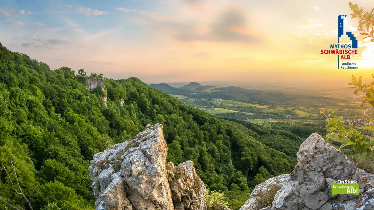 Sonnenuntergang über grünen Hügeln und Felsen. Ein perfekter Ort zum Wandern in Reutlingen, mit Blick auf das weite Tal.